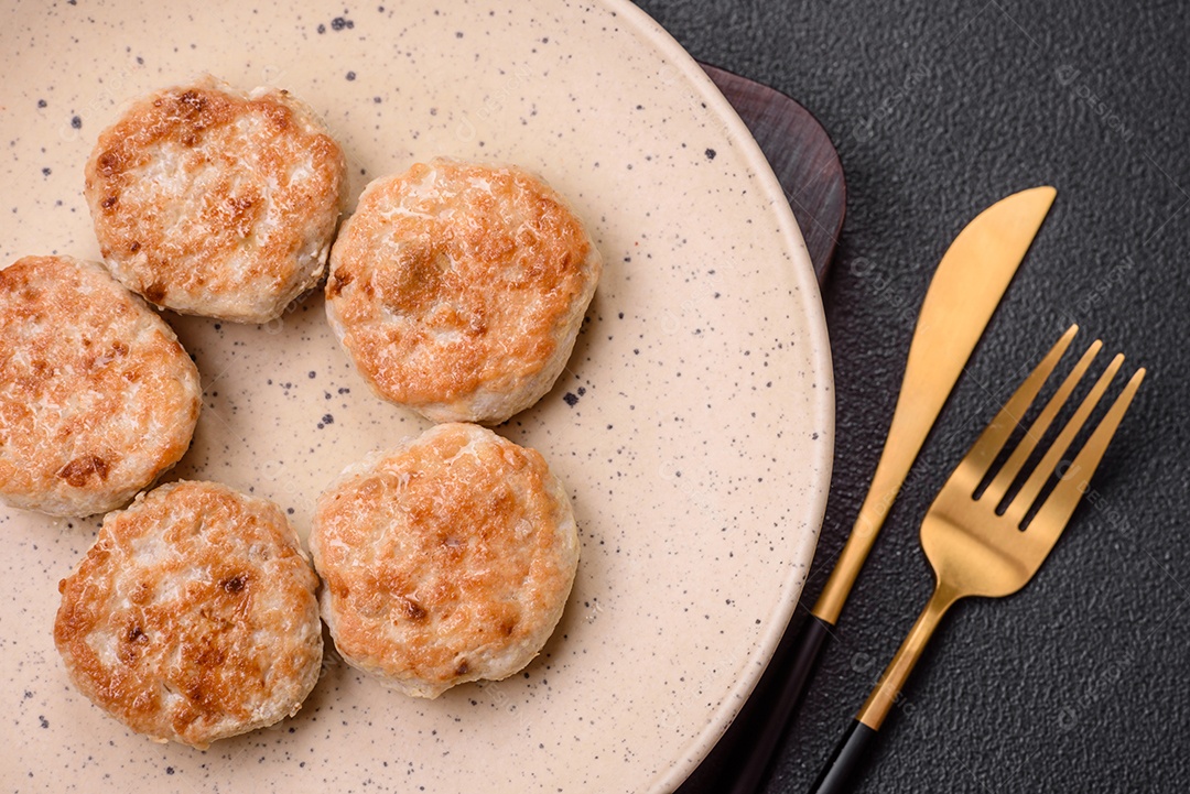 Almôndegas fritas de carne picada, carne de porco ou frango com sal, especiarias e ervas sobre um fundo escuro de concreto