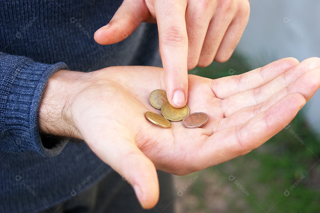 Homem contando moedas europeias nas mãos