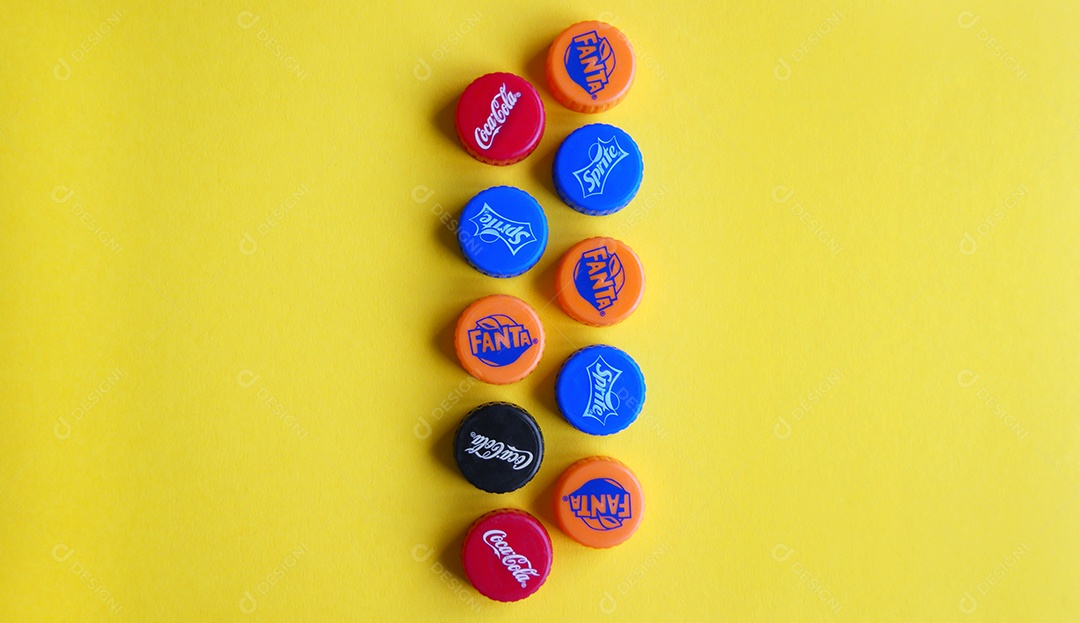 Várias tampas de refrigerantes em filas sobre fundo amarelo