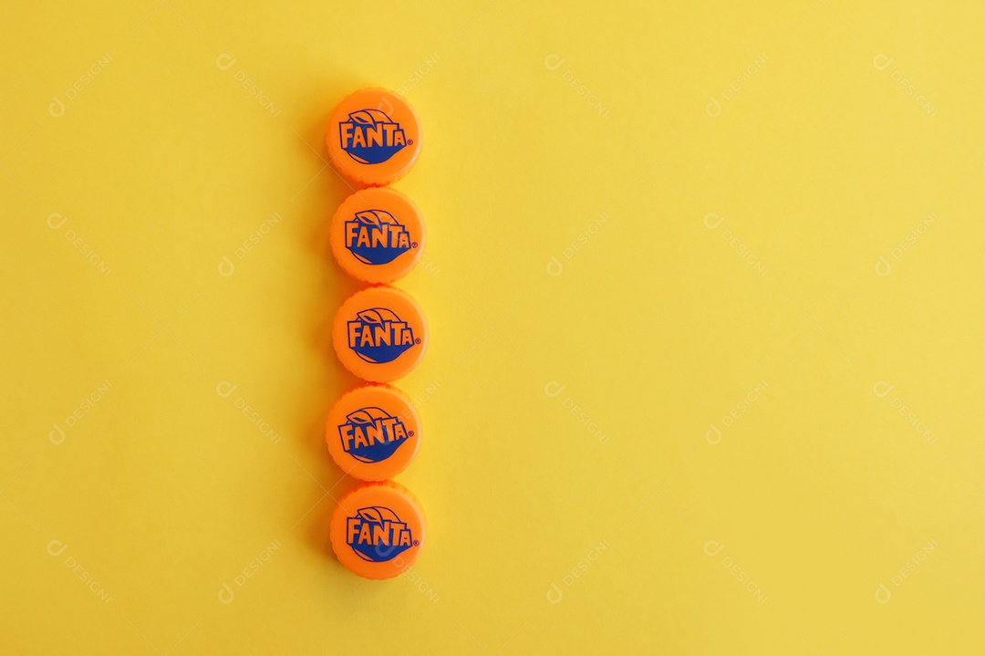 Tampas de garrafa pet da Fanta em fileira sobre fundo amarelo