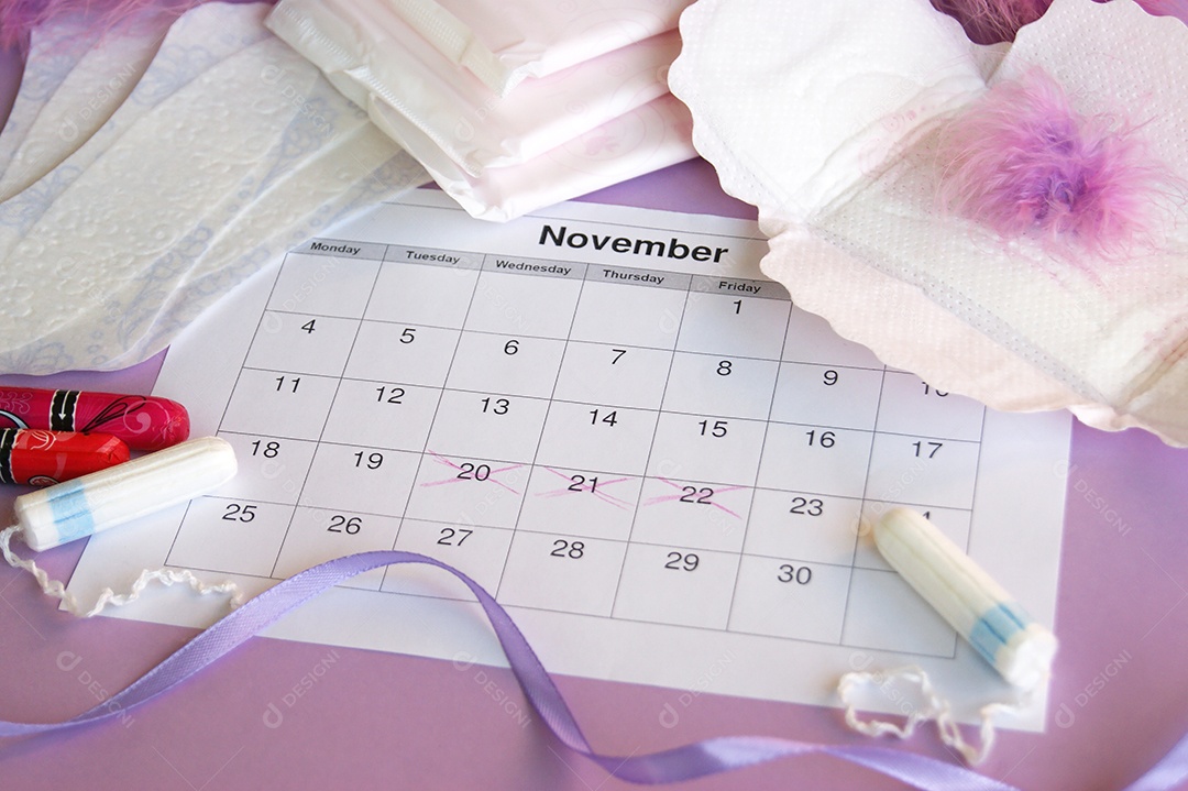 Os absorventes menstruais e tampões no calendário do período menstrual com fundo lilás.