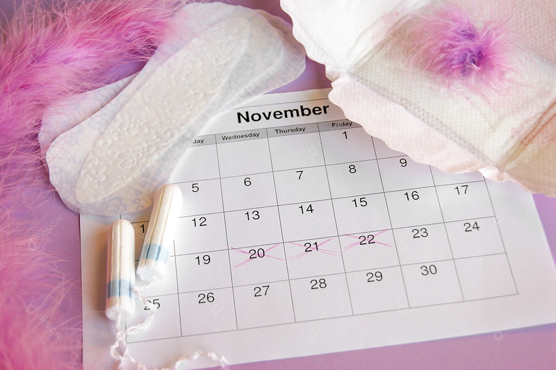 Os absorventes menstruais e tampões no calendário do período menstrual com fundo lilás.