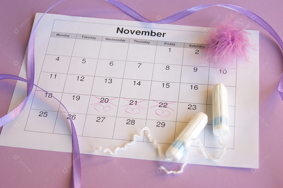Os absorventes menstruais e tampões no calendário do período menstrual com fundo lilás.