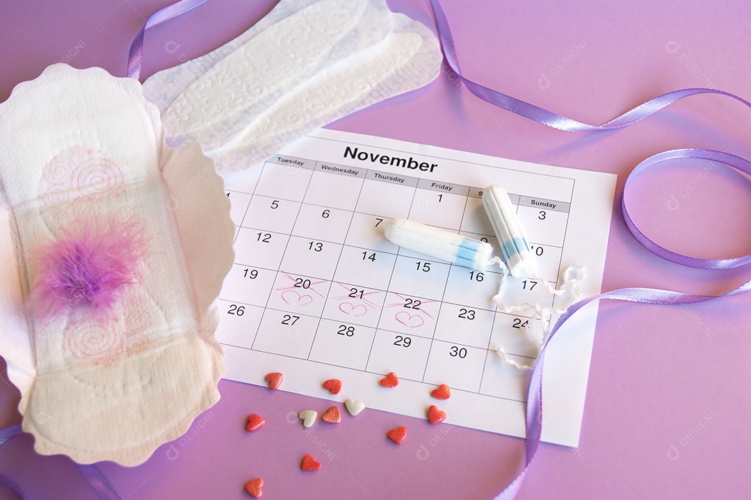 Os absorventes menstruais e tampões no calendário do período menstrual com fundo lilás.