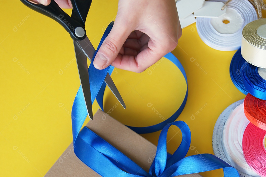 Mãos cortando fita de cetim da caixa de presente