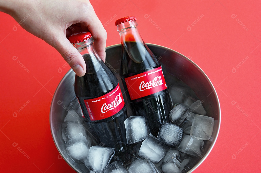 Mão segurando coca cola gelada em balde com gelo