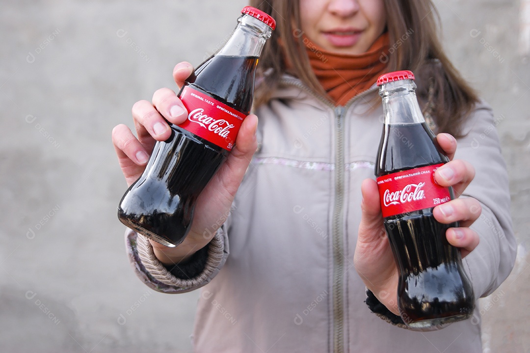 Mulher segurando duas coca-cola de garrafa