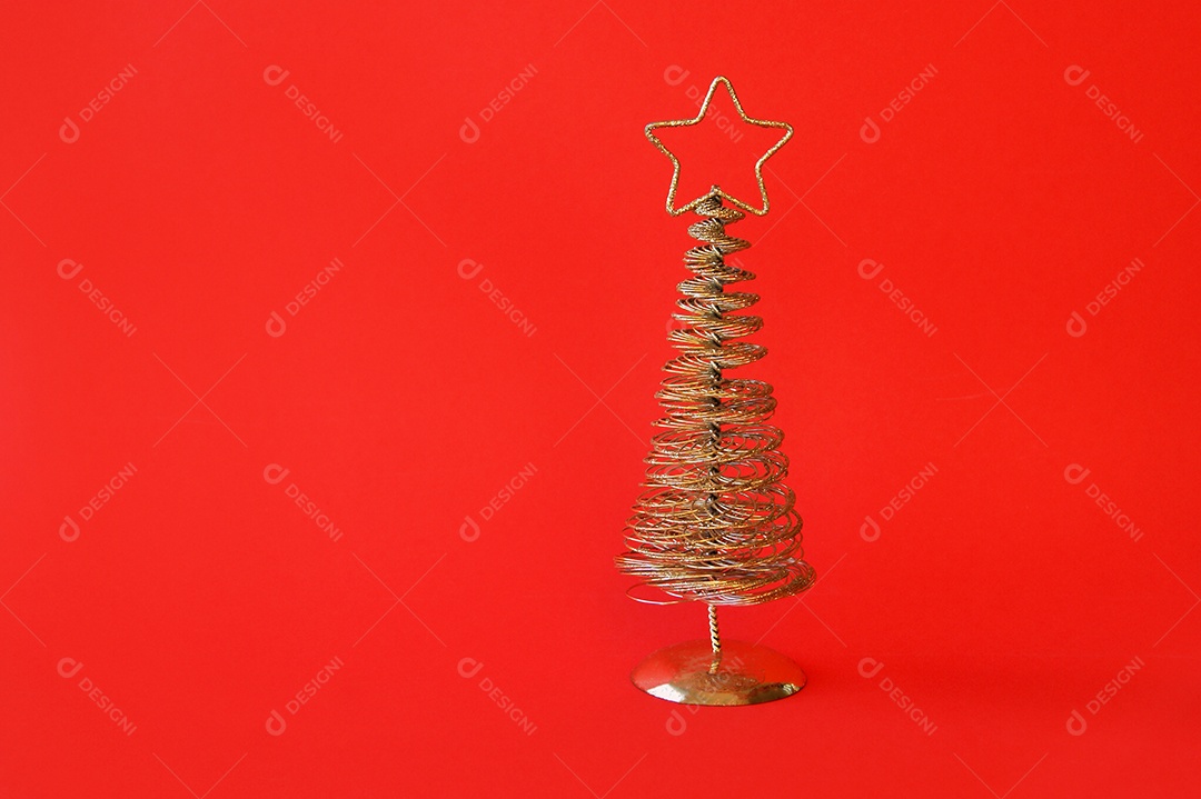 Árvore de Natal de metal dourado com uma estrela no topo fundo vermelho
