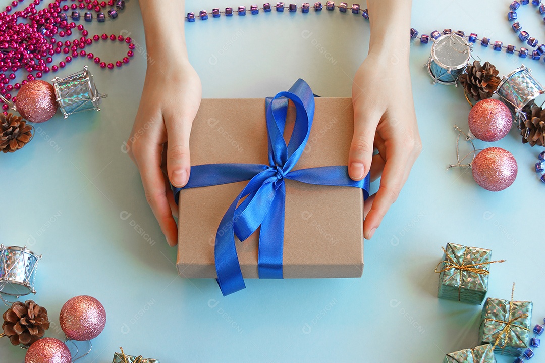 Mãos segurando caixa de presente e fundo decorado de natal