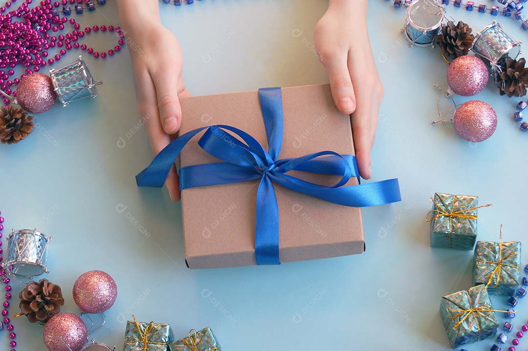 Mãos segurando caixa de presente e fundo decorado de natal