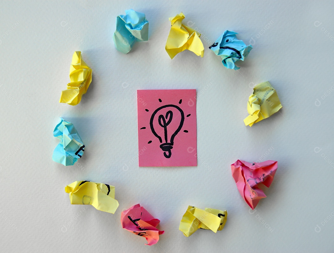 Papel post it ao centro e vários outros amassado ao redor