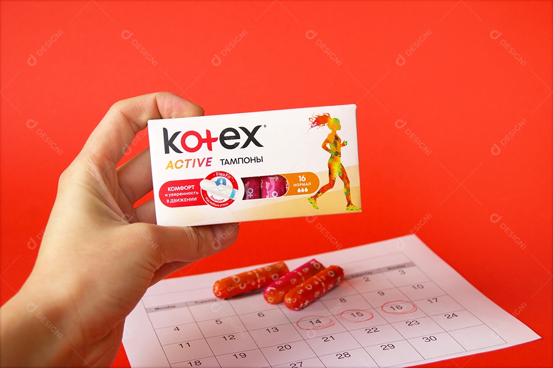 Mão segurando caixa de absorvente ob kortex sobre fundo vermelho