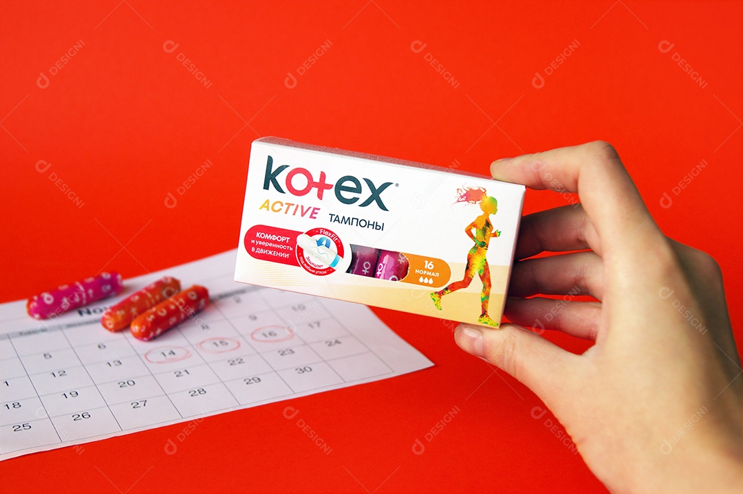 Mão segurando caixa de absorvente ob kortex sobre fundo vermelho