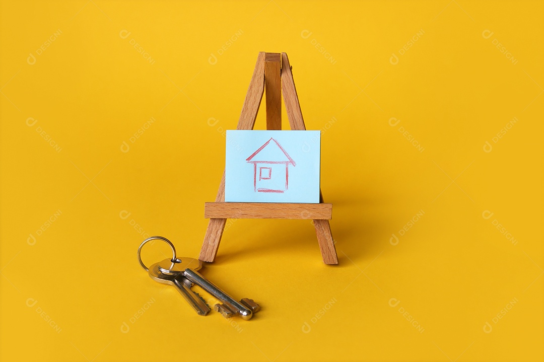 Desenho de uma casa em cima de cavalete de madeira e chaves de lado sobre fundo amarelo