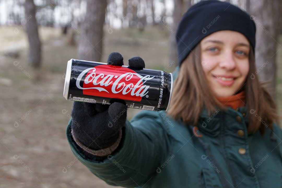 Mulher segurando coca-cola de lata sobre fundo de natureza