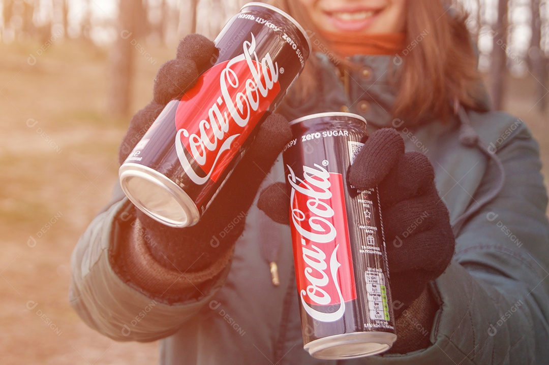 Mulher segurando duas coca-cola de lata