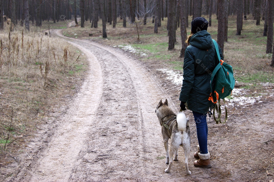 Jovem caminha pela floresta com um cachorro