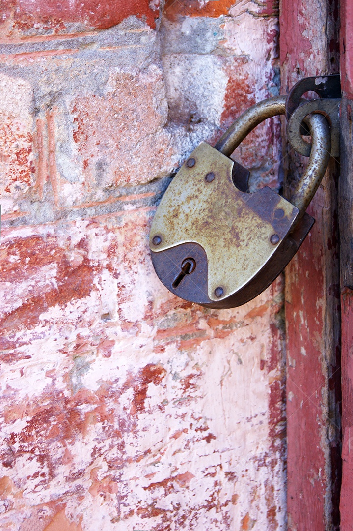 Um cadeado velho em portas fechada parede de tijolo