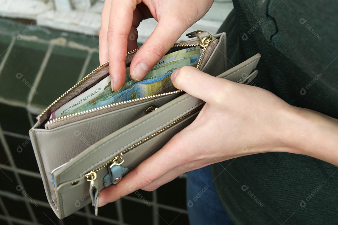 Mãos femininas escolhendo hryvnia ucraniana na carteira