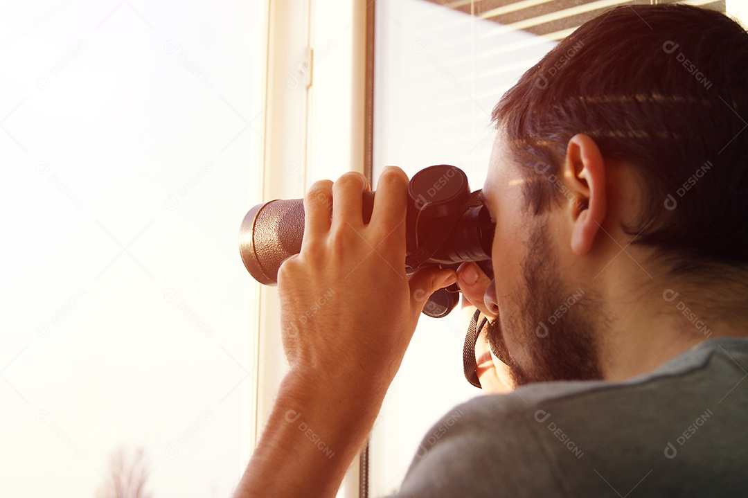 Jovem olhando através de um binoculo algo á distancia