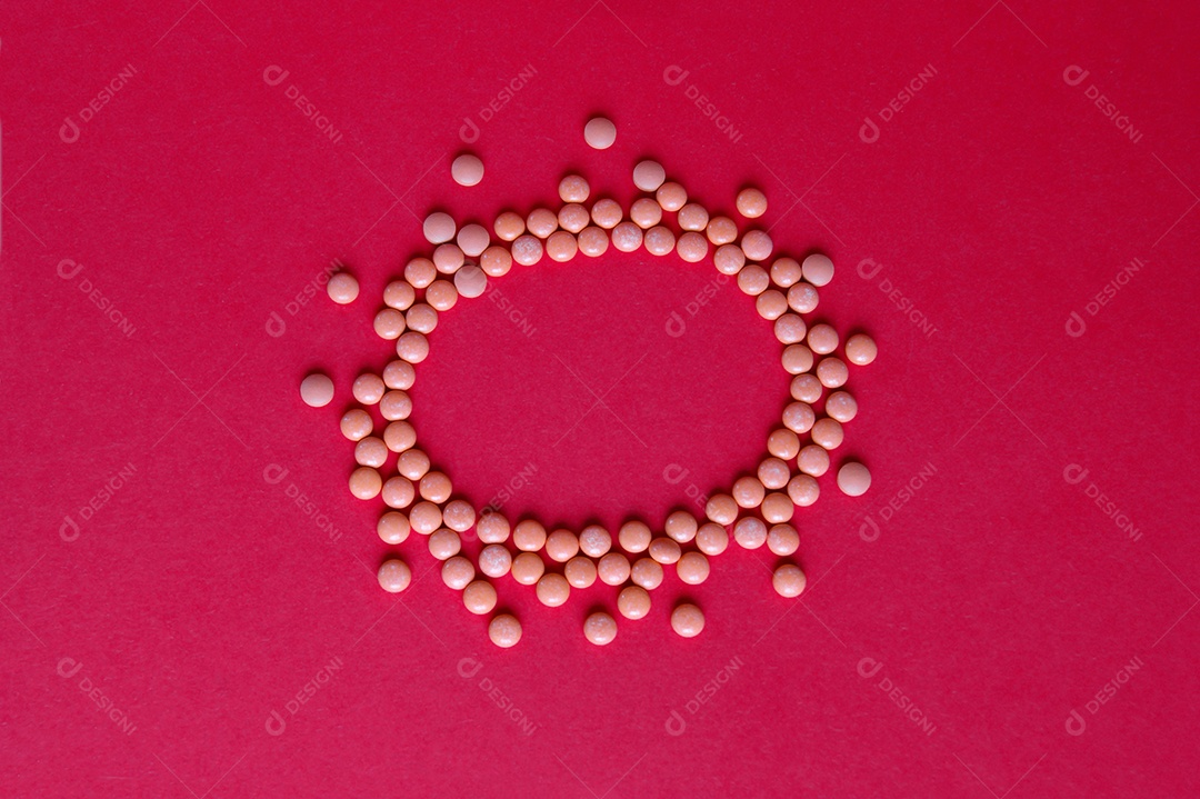 Remédios e comprimidos espalhados em circulo sobre fundo vermelho