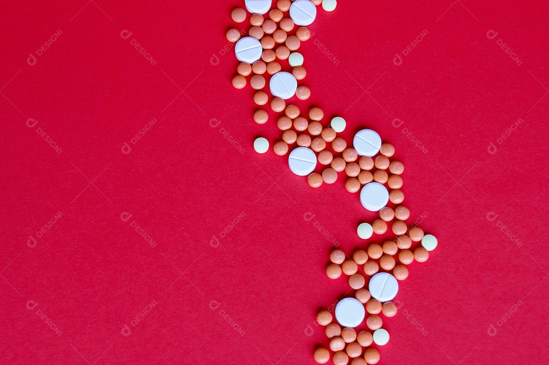 Remédios e comprimidos espalhados sobre fundo vermelho