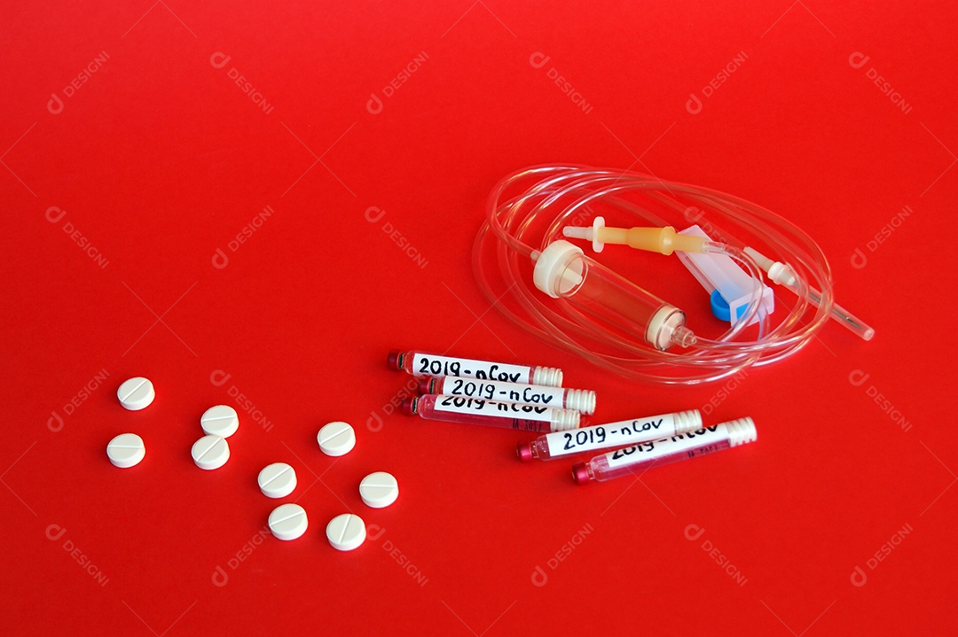 Tubos coletores e cateter e comprimidos sobre fundo vermelho
