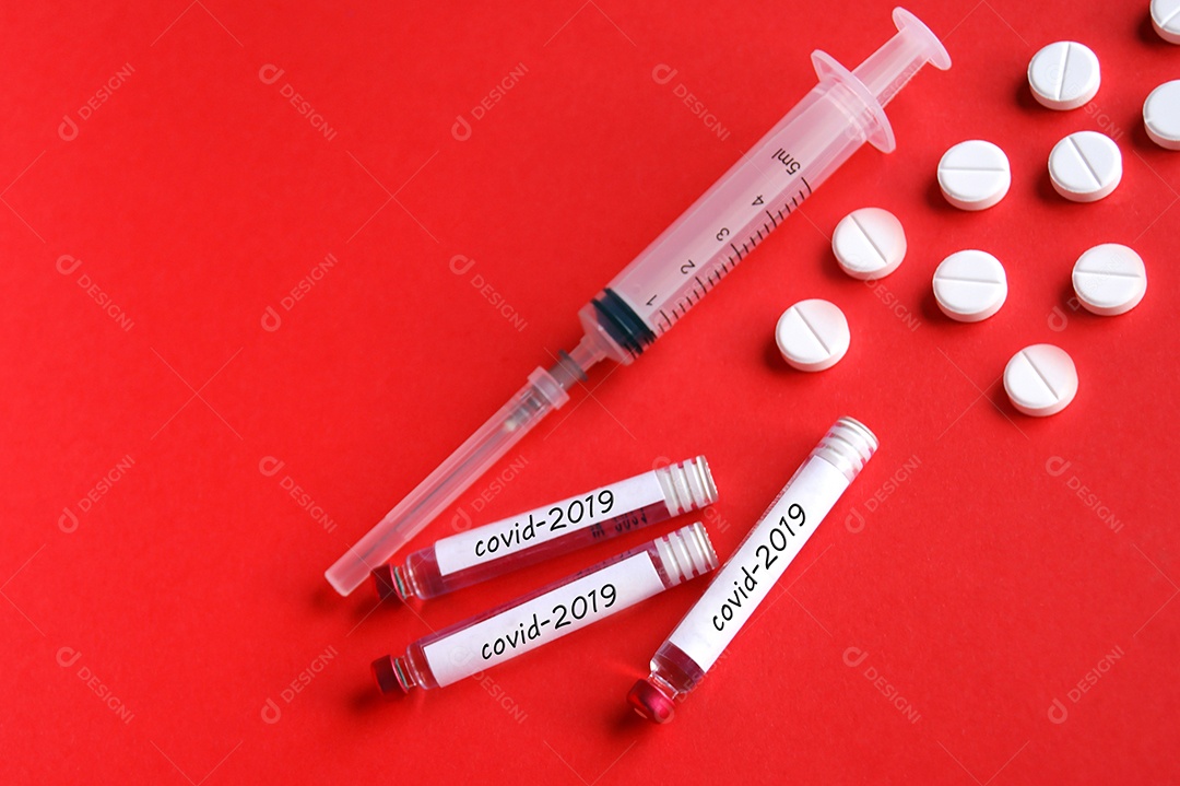 Tubos coletores seringa com agulha e comprimidos sobre fundo vermelho