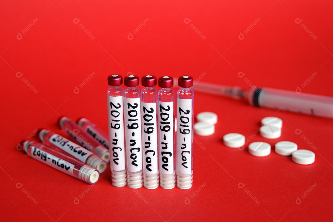 Tubos coletores seringa com agulha e comprimidos sobre fundo vermelho