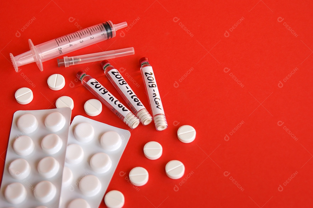 Cartelas de remédios seringa agulha e tubo coletores sobre fundo vermelho