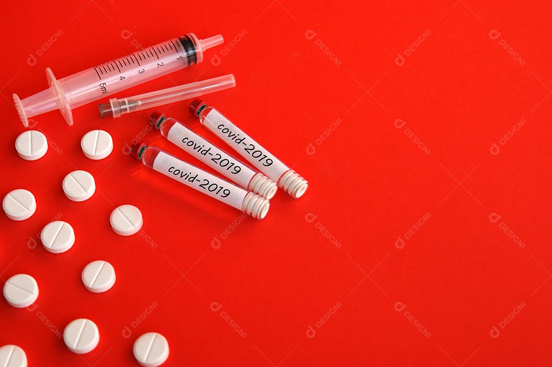 Comprimidos tubos coletores seringa e agulha sobre fundo vermelho