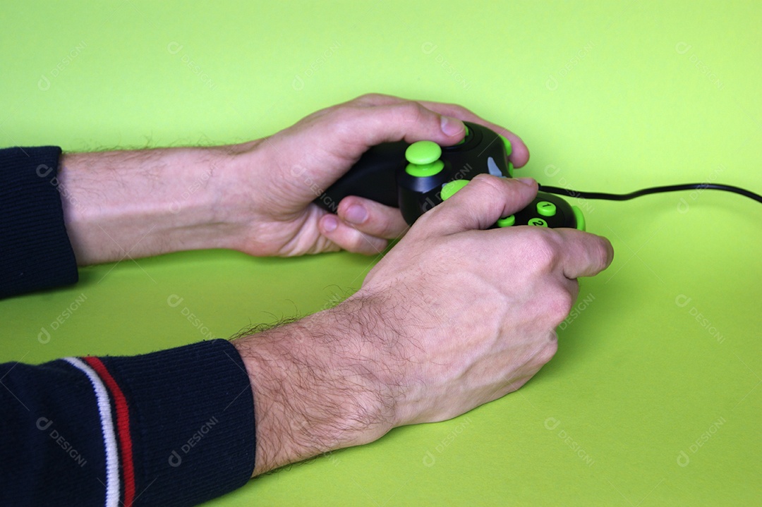 Mãos masculinas segurando controle de videgame sobre fundo verde