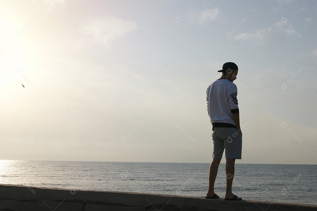 Homem de boné de frente para o mar