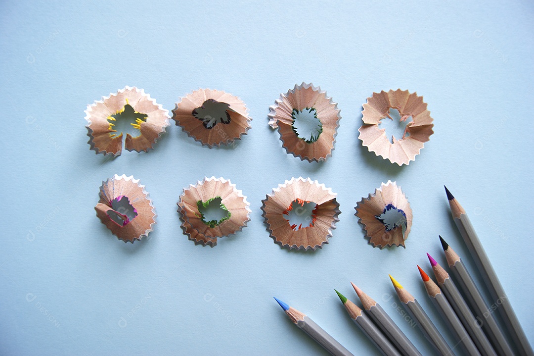 Lápis de colorir e casca de lápis apontadas em fundo isolado azul claro