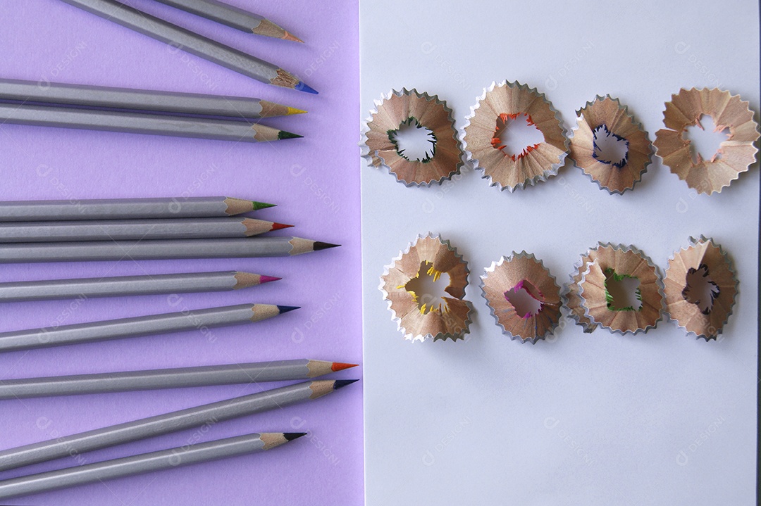 Lápis de colorir com caderno e casca de lápis apontados em cima