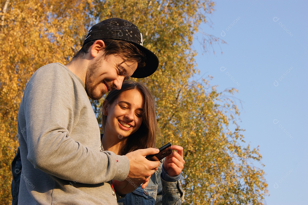 Casal olhando celular e sorrindo juntos
