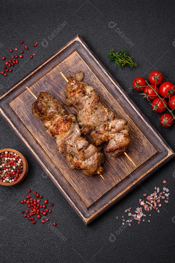 Delicioso espetinho frito de frango ou carne de porco com sal, especiarias e ervas sobre um fundo escuro de concreto