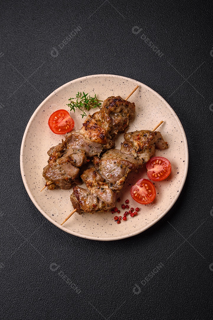 Delicioso espetinho frito de frango ou carne de porco com sal, especiarias e ervas sobre um fundo escuro de concreto