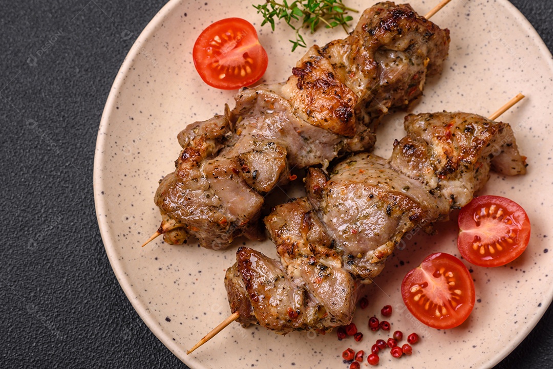 Delicioso espetinho frito de frango ou carne de porco com sal, especiarias e ervas sobre um fundo escuro de concreto