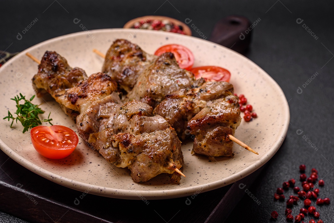 Delicioso espetinho frito de frango ou carne de porco com sal, especiarias e ervas sobre um fundo escuro de concreto
