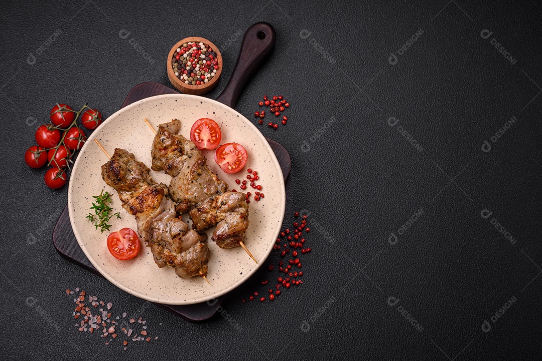Delicioso espetinho frito de frango ou carne de porco com sal, especiarias e ervas sobre um fundo escuro de concreto