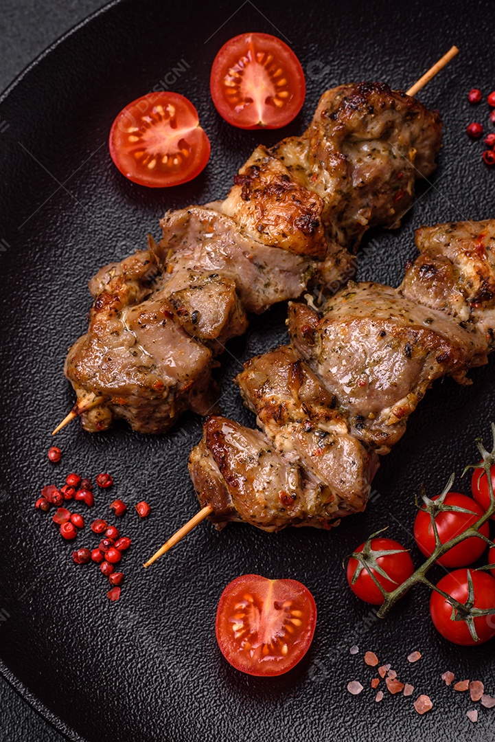 Delicioso espetinho frito de frango ou carne de porco com sal, especiarias e ervas sobre um fundo escuro de concreto
