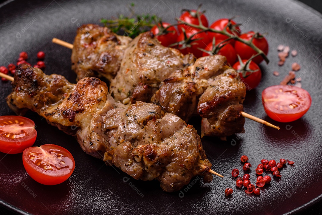 Delicioso espetinho frito de frango ou carne de porco com sal, especiarias e ervas sobre um fundo escuro de concreto