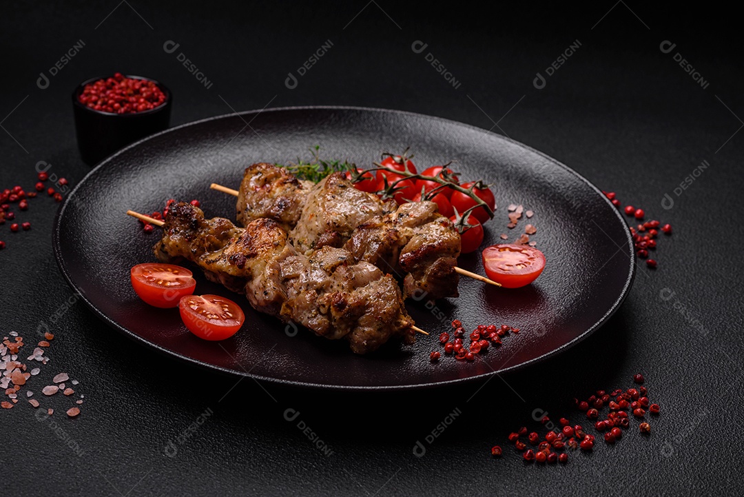 Delicioso espetinho frito de frango ou carne de porco com sal, especiarias e ervas sobre um fundo escuro de concreto