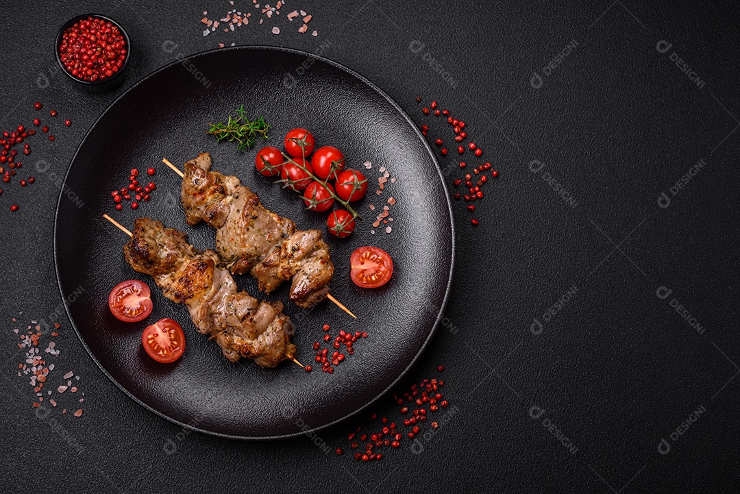 Delicioso espetinho frito de frango ou carne de porco com sal, especiarias e ervas sobre um fundo escuro de concreto