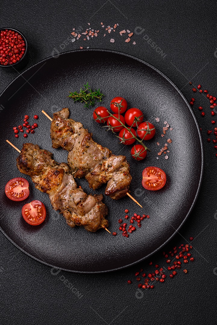 Delicioso espetinho frito de frango ou carne de porco com sal, especiarias e ervas sobre um fundo escuro de concreto