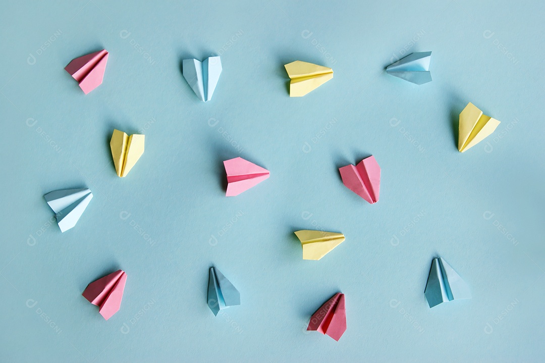 Aviões de papel multicoloridos sobre fundo azul claro