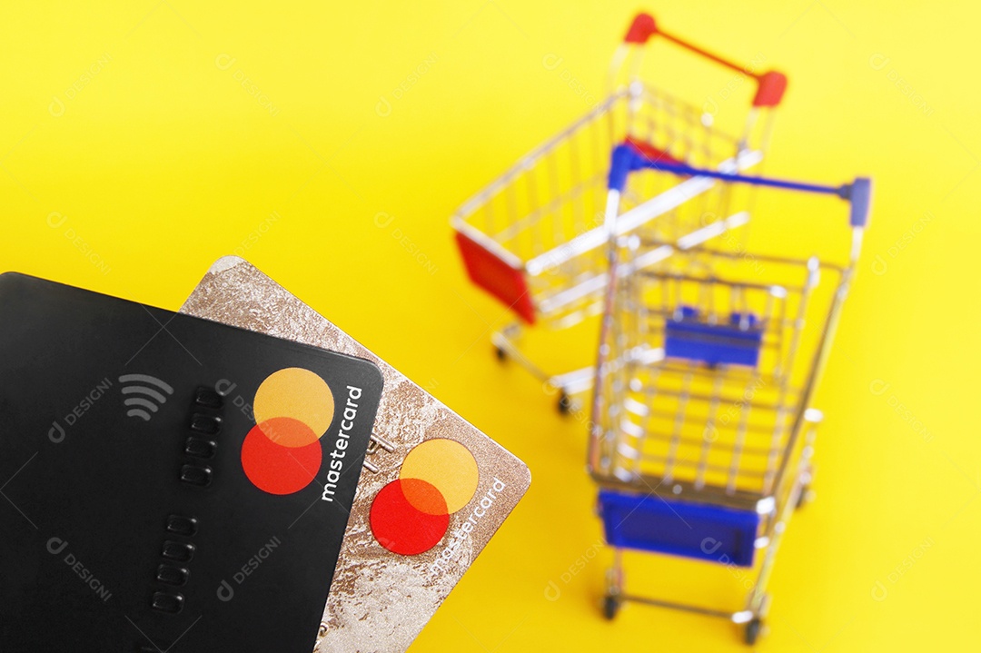 Cartões de crédito e carrinhos de compra sobre fundo amarelo