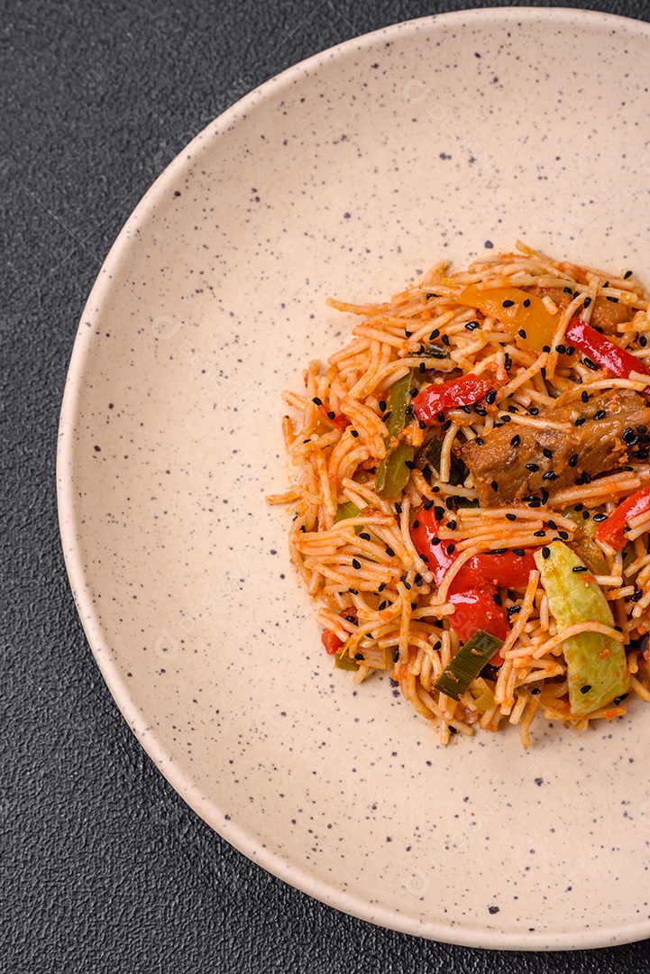 Delicioso macarrão udon com carne ou frutos do mar, legumes, sal e especiarias sobre um fundo escuro de concreto