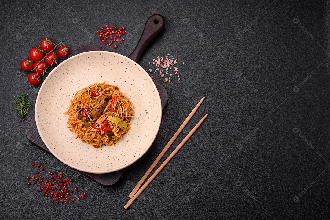 Delicioso macarrão udon com carne ou frutos do mar, legumes, sal e especiarias sobre um fundo escuro de concreto